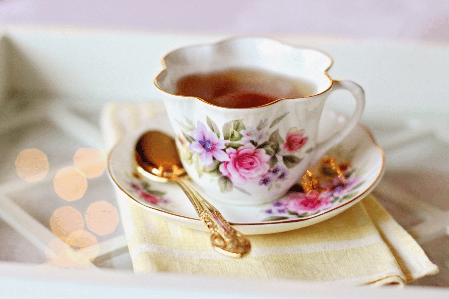 cup of tea in a floral cup sitting on a saucer with a spoon